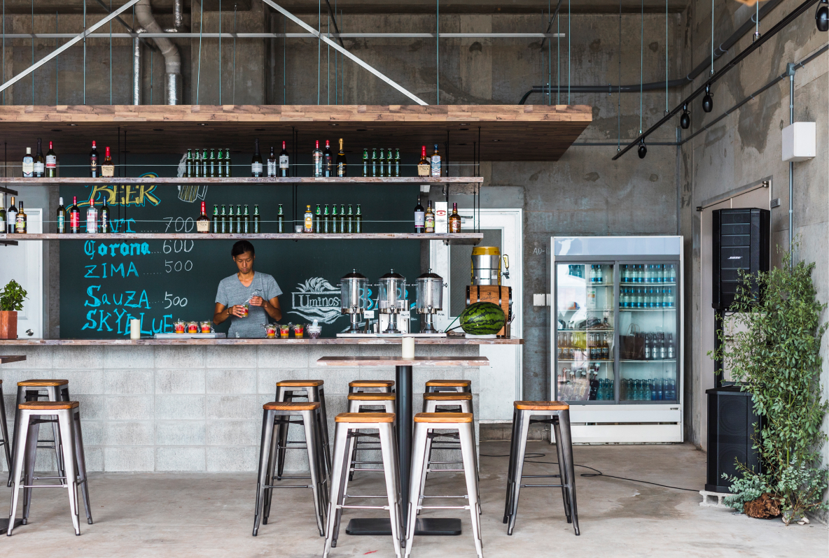 写真：コンクリートを基調としたサンセットカフェ店内、テーブル席とカウンター席があります