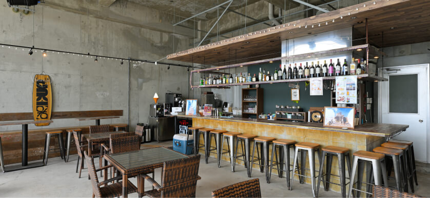 写真：コンクリートを基調としたサンセットカフェ店内、テーブル席とカウンター席があります