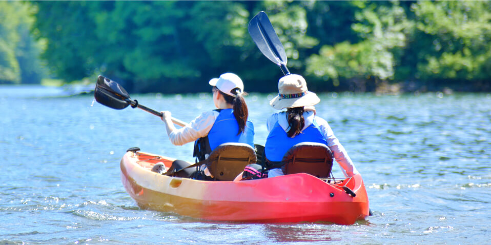 写真：女性2人が海でカヌーを漕いでいる様子
