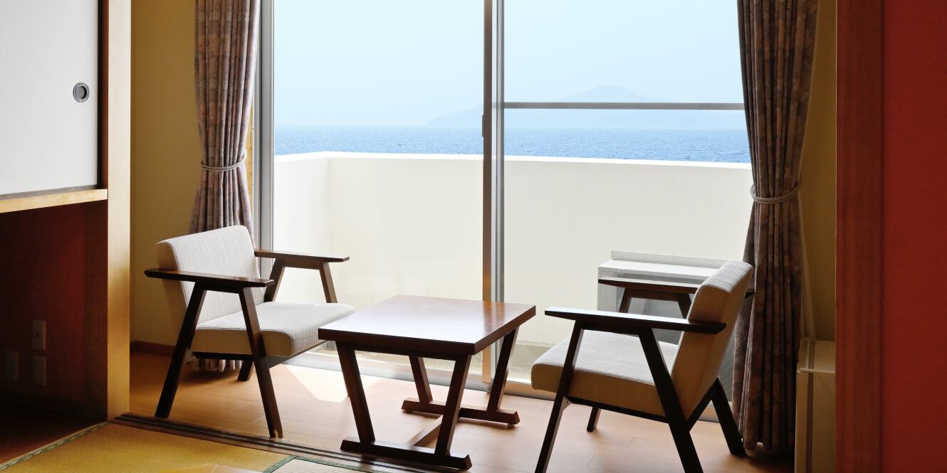 写真：海が見える窓側に椅子2台と机が設置された和室10畳の客室
