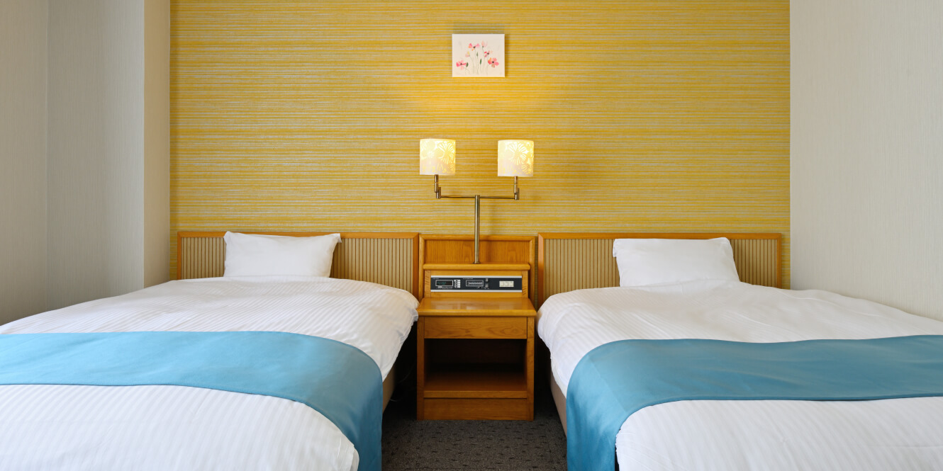 写真：2台のベッドが並び、間接照明が真ん中に設置された洋室